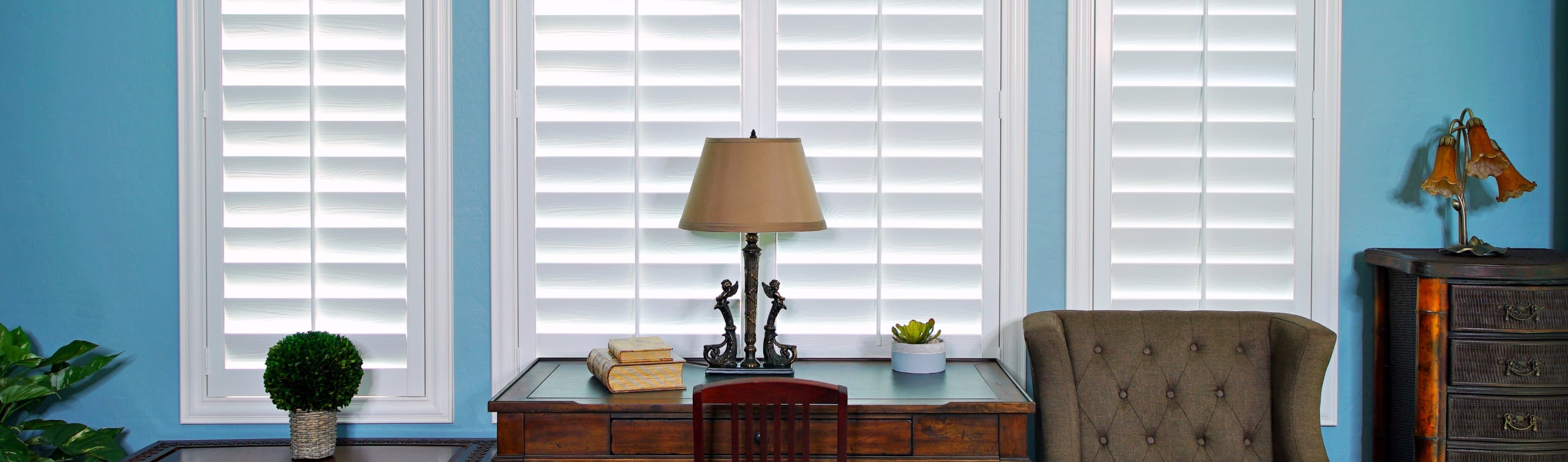 White plantation shutters next to blue walls